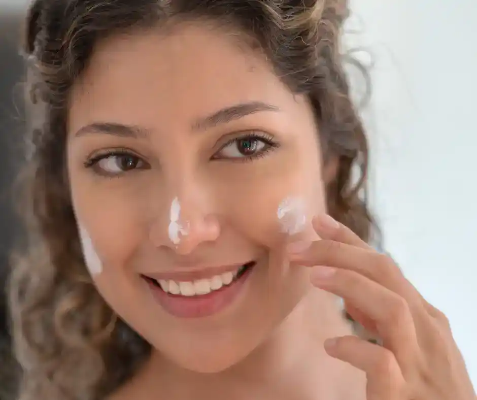 woman applying sunscreen to prevent facial spider veins